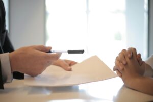 Man handing a document to another person to sign