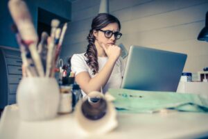 Woman sitting in front of her laptop, expressing concern