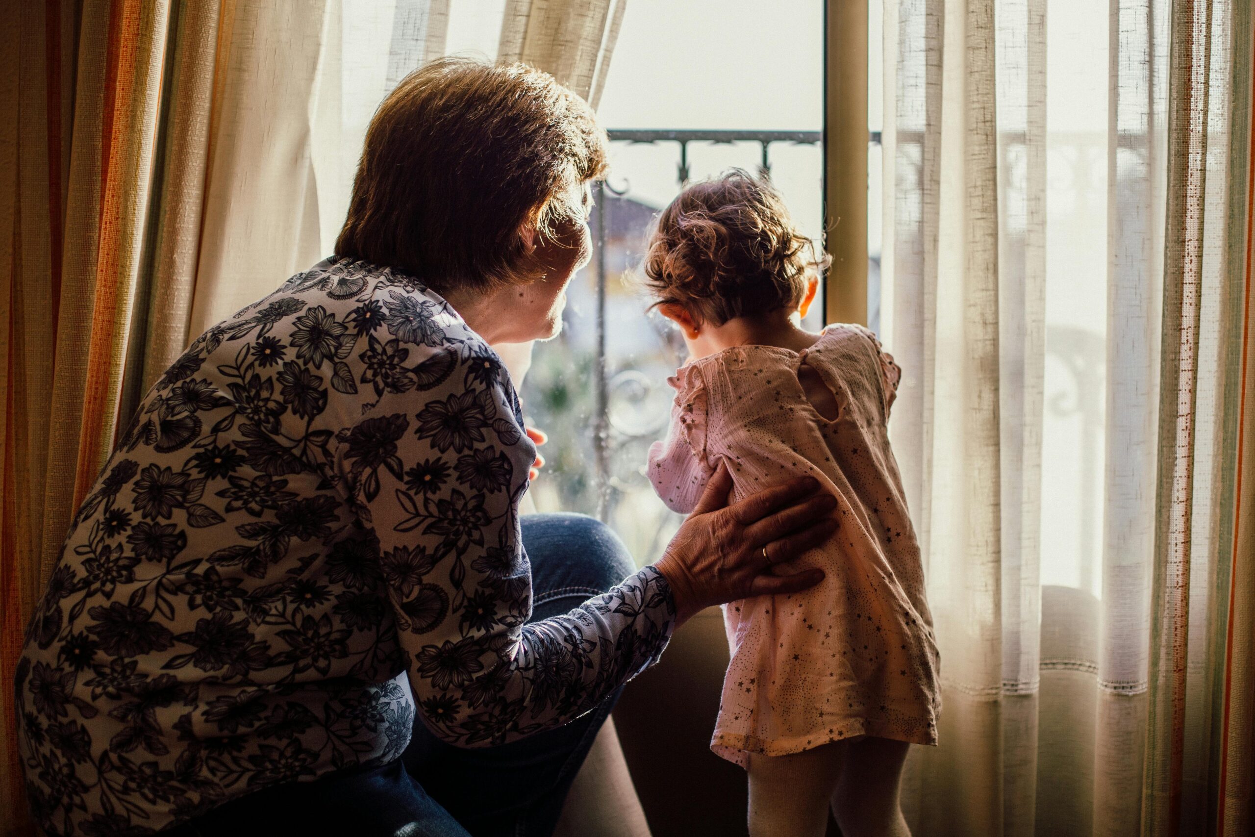 Grandmother and granddaughter looking out the window.