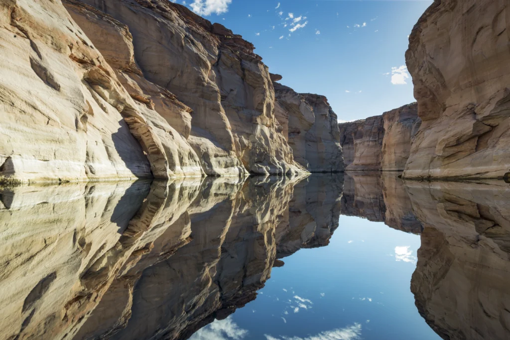 Red sandstone canyon walls reflected in still water at a Utah lake, similar to Lake Powell.